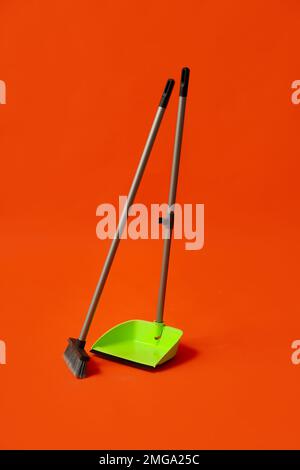 Paletta in plastica con scopa per pulizia su sfondo colorato Foto Stock