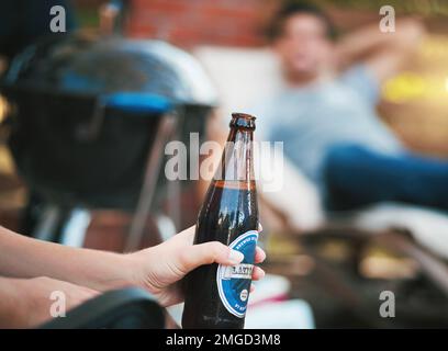 Il fine settimana è appena iniziato. una donna che tiene una bottiglia di birra in un incontro. Foto Stock