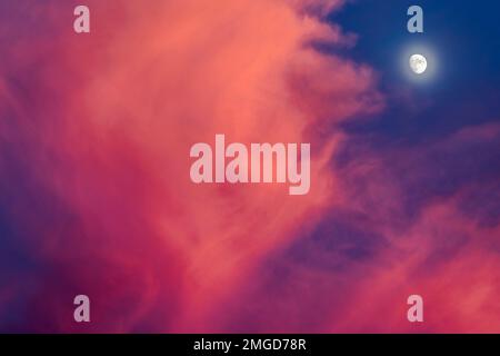 Luna al tramonto con le nuvole rosa e arancione lanuginose Foto Stock