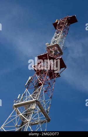 Antenna per telecomunicazioni per radio, televisione e telefonia con nuvola e cielo blu. Foto Stock