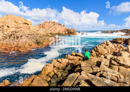 Persone che guardano il picco di marea d'acqua attraverso lo stretto canale di granito di Canal Rocks, Leeuwin-Naturaliste National Park, Australia Occidentale Foto Stock