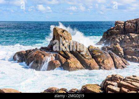 Onde che si infrangono su rocce metamorfiche di granito gneiss lungo la costa di Yallingup nell'Australia Occidentale Foto Stock