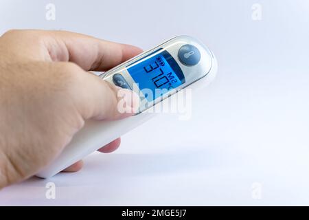 Mano umana tenere un termometro digitale a infrarossi per la scansione della temperatura corporea da Coronavirus malattia COVID-19, influenza, febbre o altre malattie. Assistenza sanitaria Foto Stock