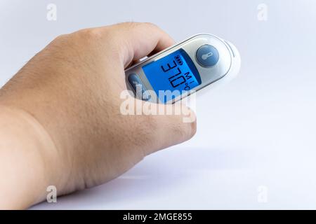 Mano umana tenere un termometro digitale a infrarossi per la scansione della temperatura corporea da Coronavirus malattia COVID-19, influenza, febbre o altre malattie. Assistenza sanitaria Foto Stock