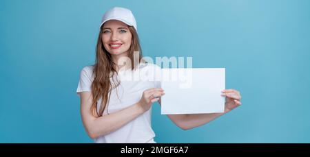 Donna felice che tiene la brochure con copertina vuota su sfondo blu indossando t-shirt bianca e cappuccio per mockup, vista dall'alto. DIP per la progettazione Foto Stock