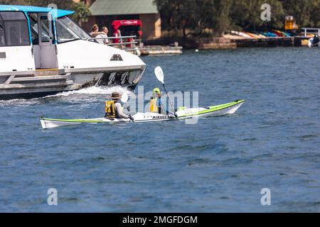 Coppia di mezza età esercizio in kayak oceanico a Mirage 730 su Pittwater, mentre la Scozia Island Church Point traghetto passa, Sydney, NSW, Australia Foto Stock