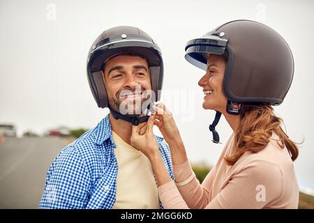 Il divertimento inizia quando il casco si accende. una donna che aggiusta il casco dei suoi fidanzati. Foto Stock