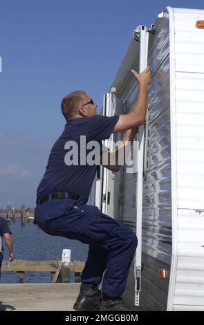 Guardia costiera sui danni delle scene - 26-HK-82-7. CG on Scene Damages --Coast Guardsman arrampicata su RV, 051021. Uragano Katrina Foto Stock