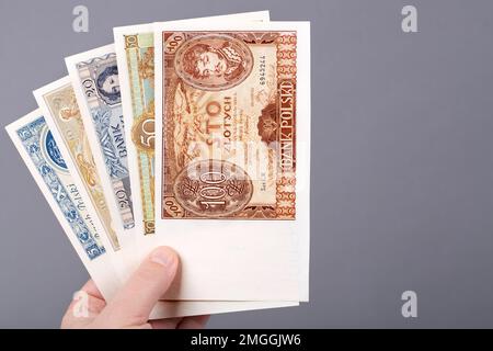 Vecchio denaro polacco - Zloty in mano su uno sfondo grigio Foto Stock