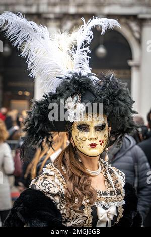 Una donna in costume medievale scuro, una maschera di carnevale femminile e  un grande cappello chic con piume al carnevale di Venezia Foto stock - Alamy