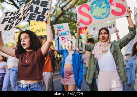 Gruppo di attivisti giovanili che si oppongono al cambiamento climatico e al riscaldamento globale. Giovani multiculturali che protestano con manifesti e striscioni. Subacquei Foto Stock