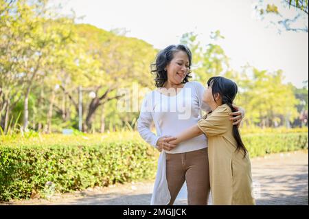 Felice e gioiosa nonna e nipote asiatica mostrando amore, abbracciando, avendo un grande tempo insieme nel parco della città. Foto Stock