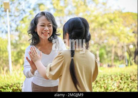 Felice nonna asiatica e nipote divertirsi insieme, giocare giochi divertenti, trascorrere il fine settimana insieme nel parco. Foto Stock