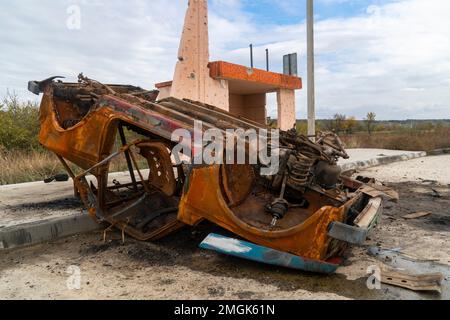 Campagna. Un'auto civile bruciata rovesciata si trova in una stazione degli autobus. Guerra in Ucraina. Invasione russa dell'Ucraina. Crimini di guerra Foto Stock