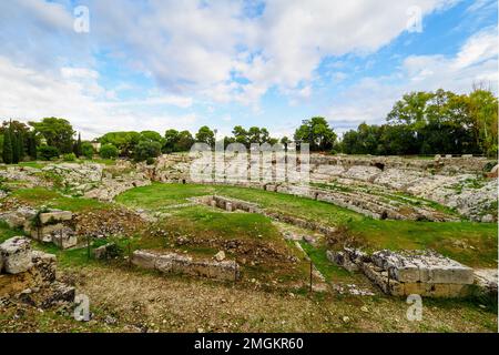 Anfiteatro Romano di Siracusa - i sec. AD - III sec. AD - Parco Archeologico della Neapolis - Siracusa, Sicilia, Italia l'anfiteatro ha due ingressi ed è servito da un complesso sistema di scale che scendono dal piano superiore situato all'esterno. L'arena era dotata, al centro, di una grande sala rettangolare, originariamente coperta, collegata tramite un passaggio sotterraneo con l'estremità meridionale del monumento, sull'asse del corridoio d'ingresso. Intorno all'arena la cavea si distingue per un alto podio, dietro il quale corre un corridoio coperto con cancelli di accesso all'arena per i gladiatori A. Foto Stock