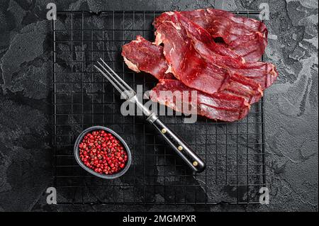 Basturma essiccato a fette, carne di manzo curata pronta per mangiare. Sfondo nero. Vista dall'alto Foto Stock