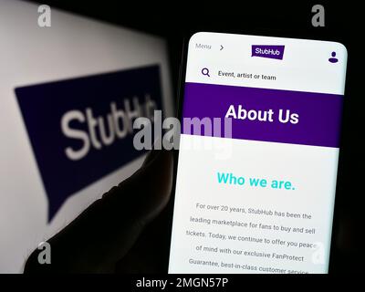 Persona che tiene il cellulare con il sito web della società di biglietteria US StubHub sullo schermo di fronte al logo aziendale. Messa a fuoco al centro del display del telefono. Foto Stock