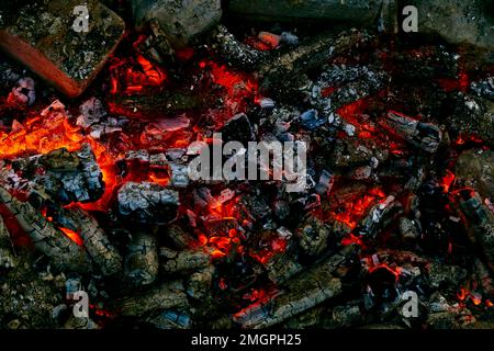 Falò con fiamma sbiadita e carboni brucianti. Tempo per cucinare carne. Foto Stock