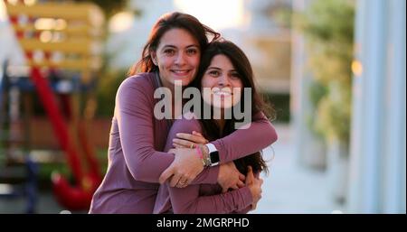 Due sorelle adulte felici che si posano insieme fuori gemelle con gli stessi vestiti Foto Stock