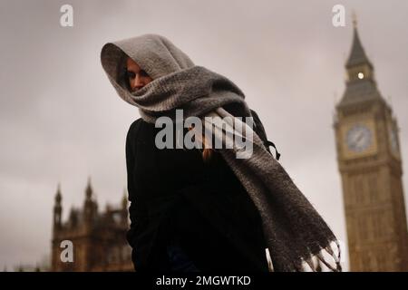 Una donna si copre contro il tempo umido e ventoso sul Westminster Bridge nel centro di Londra. Data immagine: Giovedì 26 gennaio 2023. Foto Stock