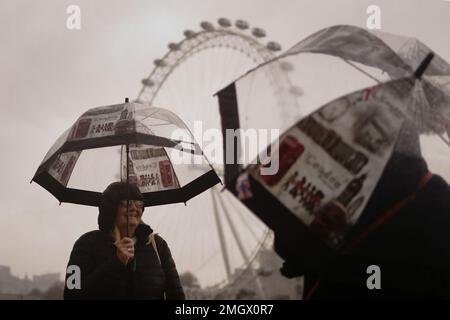 Due turisti si coprono contro il tempo umido e ventoso sul Westminster Bridge nel centro di Londra. Data immagine: Giovedì 26 gennaio 2023. Foto Stock