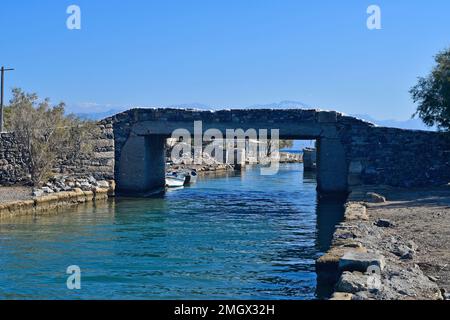 Grecia, Creta, piccolo ponte stradale su un canale per le barche da pesca alla penisola di Kalydon con un ristorante sulla riva Foto Stock