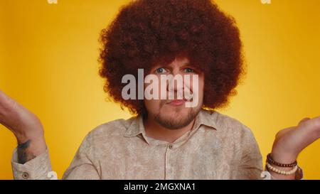 Perché. Uomo irritato sincero con lussureggianti capelli afro alzando le mani in indignante espressione chiedendo motivo di fallimento dimostrando incredulità irritazione da difficoltà. Ragazzo confuso su sfondo giallo Foto Stock