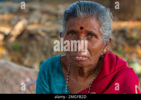 Puttaarthi, India - Gennaio 21,2023: Vecchia signora indiana con capelli grigi, primo piano, guardando in macchina fotografica ad un mercato di verdure a Puttaarthi Foto Stock