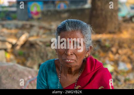 Puttaarthi, India - Gennaio 21,2023: Vecchia signora indiana con capelli grigi, primo piano, guardando in macchina fotografica ad un mercato di verdure a Puttaarthi Foto Stock