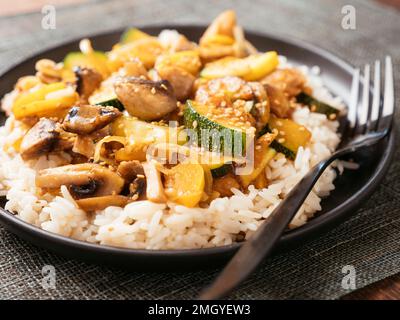 Zucchine, funghi e chickun vegano sul riso. Foto Stock