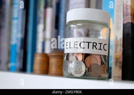 risparmio di denaro in vaso di vetro per contribuire a pagare la bolletta elettrica Foto Stock