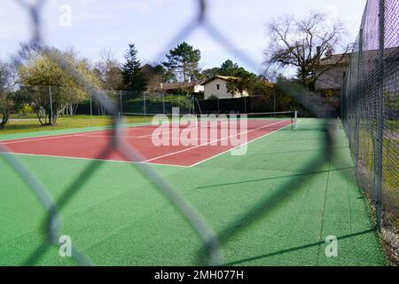 campi da tennis verde rosso privato attraverso recinzione a rete metallica Foto Stock