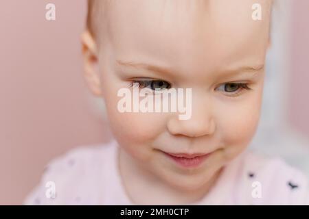 Primo piano ritratto di una bambina caucasica in pigiama rosa chiaro Foto Stock