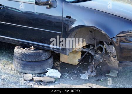 vettura nera riparata senza ruota anteriore o con ruote rubate lato strada città Foto Stock