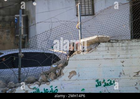 Jenin, Medio Oriente. 26th Jan, 2023. I palestinesi ispezionano i resti di strutture e veicoli distrutti, danneggiati da un bulldozer militare israeliano durante lo storming della città di Jenin nella Cisgiordania occupata. Le grandi forze dell'esercito israeliano hanno colpito la città di Jenin e hanno ucciso dieci palestinesi, tra cui una donna, e ferito più di venti altri con proiettili vivi durante gli scontri tra loro e le forze che li hanno confrontati. L'esercito ha detto che l'incursione era su un appartamento della cella nel campo profughi di Jenin, che ha avuto inizio dopo 'accurate informazioni di intelligence' fornite da t Foto Stock