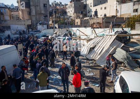 Jenin, Medio Oriente. 26th Jan, 2023. I palestinesi ispezionano i resti di strutture e veicoli distrutti, danneggiati da un bulldozer militare israeliano durante lo storming della città di Jenin nella Cisgiordania occupata. Le grandi forze dell'esercito israeliano hanno colpito la città di Jenin e hanno ucciso dieci palestinesi, tra cui una donna, e ferito più di venti altri con proiettili vivi durante gli scontri tra loro e le forze che li hanno confrontati. L'esercito ha detto che l'incursione era su un appartamento della cella nel campo profughi di Jenin, che ha avuto inizio dopo 'accurate informazioni di intelligence' fornite da t Foto Stock