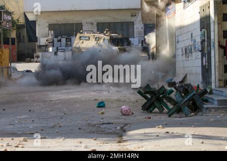 Jenin, Medio Oriente. 26th Jan, 2023. Il fumo denso sorge vicino ad un veicolo militare israeliano, dopo che una bomba fatta in casa è esplosa vicino ad esso durante lo storming della città di Jenin nella Cisgiordania occupata. Le grandi forze dell'esercito israeliano hanno colpito la città di Jenin e hanno ucciso dieci palestinesi, tra cui una donna, e ferito più di venti altri con proiettili vivi durante gli scontri tra loro e le forze che li hanno confrontati. L'esercito ha detto che l'incursione era su un appartamento della cella nel campo profughi di Jenin, che ha avuto inizio dopo 'informazioni di intelligence accurate' fornite dal servizio di sicurezza. Foto Stock