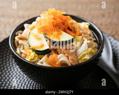 Zuppa asiatica con tagliatelle di mirne, TVP, cavolo, zucchine e carote grattugiate. Foto Stock