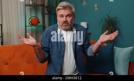 Non so cosa dire. Confuso uomo di mezza età che si sente imbarazzato circa domanda ambigua, avendo dubbi, nessuna idea, essendo clueless, incerto nel paese. Uomo anziano maturo dai capelli grigi in camera di notte Foto Stock
