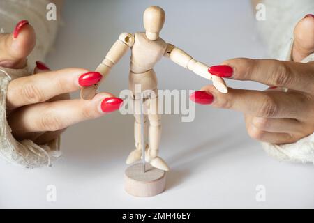 due mani femminili con polsi rotti dopo essere caduto da una bicicletta in un getto su uno sfondo isolato con manichino di legno di un uomo, mani in un ca Foto Stock