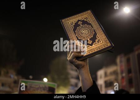 Città di Idlib, Siria. 26th Jan, 2023. Un manifestante siriano tiene in mano una copia del Corano durante una protesta contro la bruciatura del libro sacro da parte di un politico svedese. I musulmani di tutto il mondo sono indignati dopo che il politico danese-svedese Rasmus Paludan ha organizzato una manifestazione di fronte all'ambasciata turca a Stoccolma durinh, che ha bruciato una copia del santo Corano. Credit: ANAS Alkharboutli/dpa/Alamy Live News Foto Stock