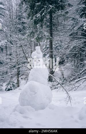 Snowman nelle foreste di montagna tra gli alberi Foto Stock