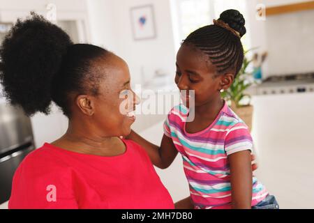 Felice afroamericana nonna e nipote abbracciare in cucina Foto Stock