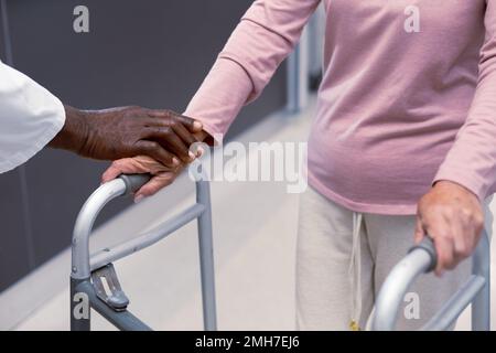 Primo piano del medico afro-americano e del paziente caucasico senior che tiene le mani Foto Stock