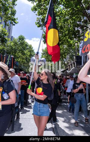 Melbourne, Australia, 26 gennaio 2023. Una giovane donna con un aborigeno con una bandiera marches durante la protesta annuale della Giornata dell'invasione a Melbourne, organizzata dagli australiani indigeni e dai loro alleati, chiede di porre fine alla celebrazione della Giornata dell'Australia e di riconoscere la sovranità indigena. Credit: Michael Currie/Speed Media/Alamy Live News Foto Stock