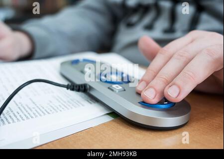 Un uomo ipovedente utilizza una macchina per la scansione e la lettura. Foto Stock