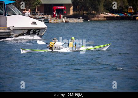 Coppia di mezza età esercizio in kayak oceanico a Mirage 730 su Pittwater, mentre la Scozia Island Church Point traghetto passa, Sydney, NSW, Australia Foto Stock