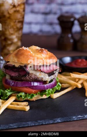 Un succulento hamburger fatto in casa sormontato da un keto e servito con patatine fritte. Foto Stock