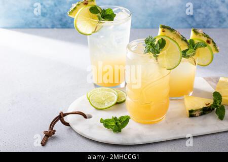 Mai tai cocktail in diversi bicchieri guarniti con ananas e lime Foto Stock