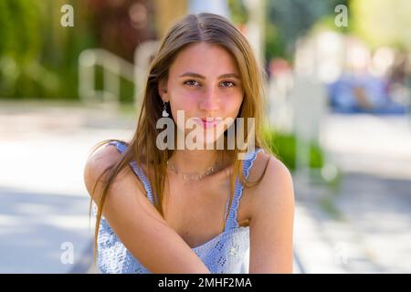 Primo piano di ragazza Teenage sorridente seduta e Pendente verso la Camera su gradini concreti di Palo Alto City Hall Plaza Foto Stock